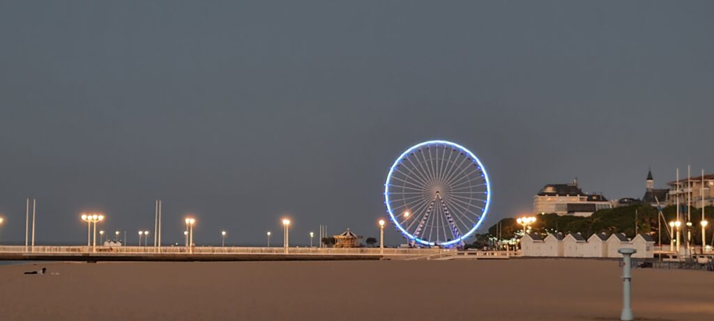 Grande roue illuminée au crépuscule avec la plage d'Arcachon au premier plan